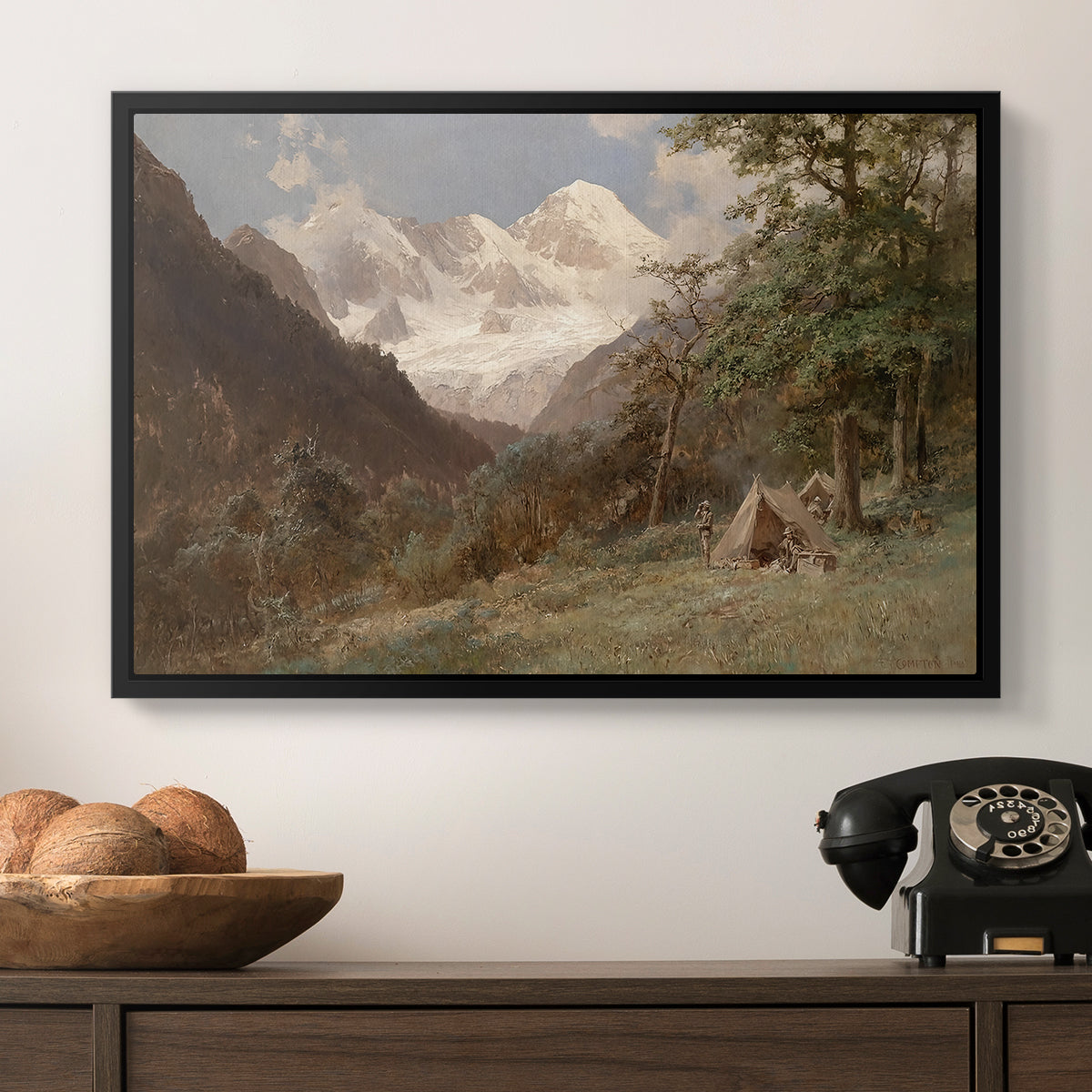 Landscape in the Caucasus, c. 1921 by Edward Theodore Compton in a black floater framed canvas displayed above a console table in a hallway, featuring a realistic depiction of remote mountain environment.