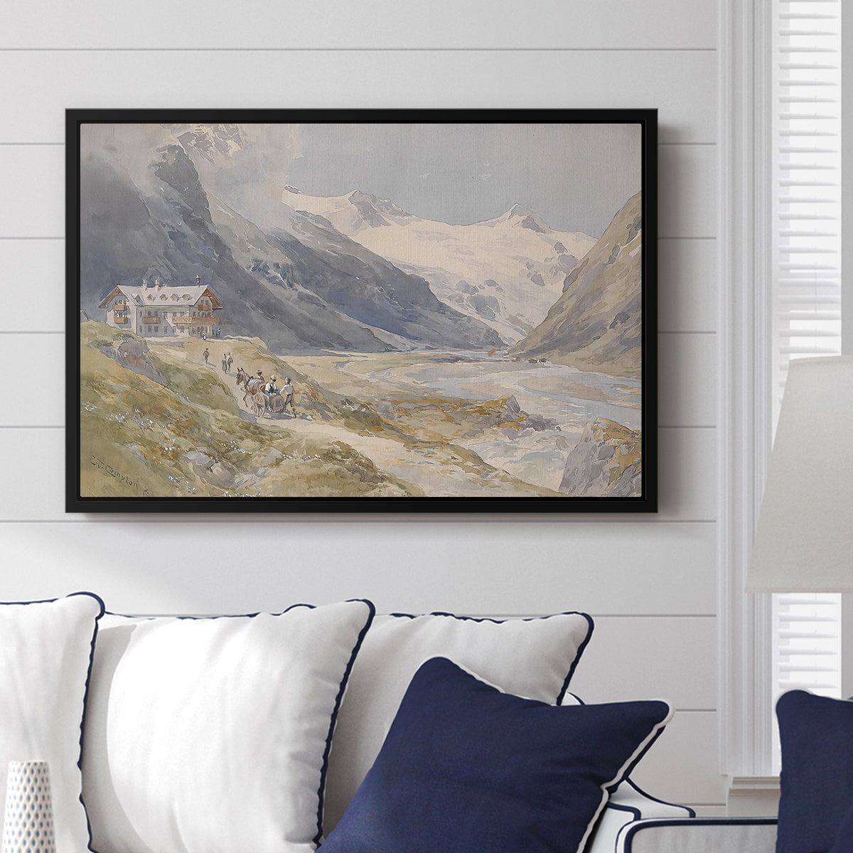 Shepherds (Pasterze), c. 1921 by Edward Theodore Compton displayed above a sofa in a living room in a black floater frame, featuring a pastoral mountain scene with figures tending livestock.