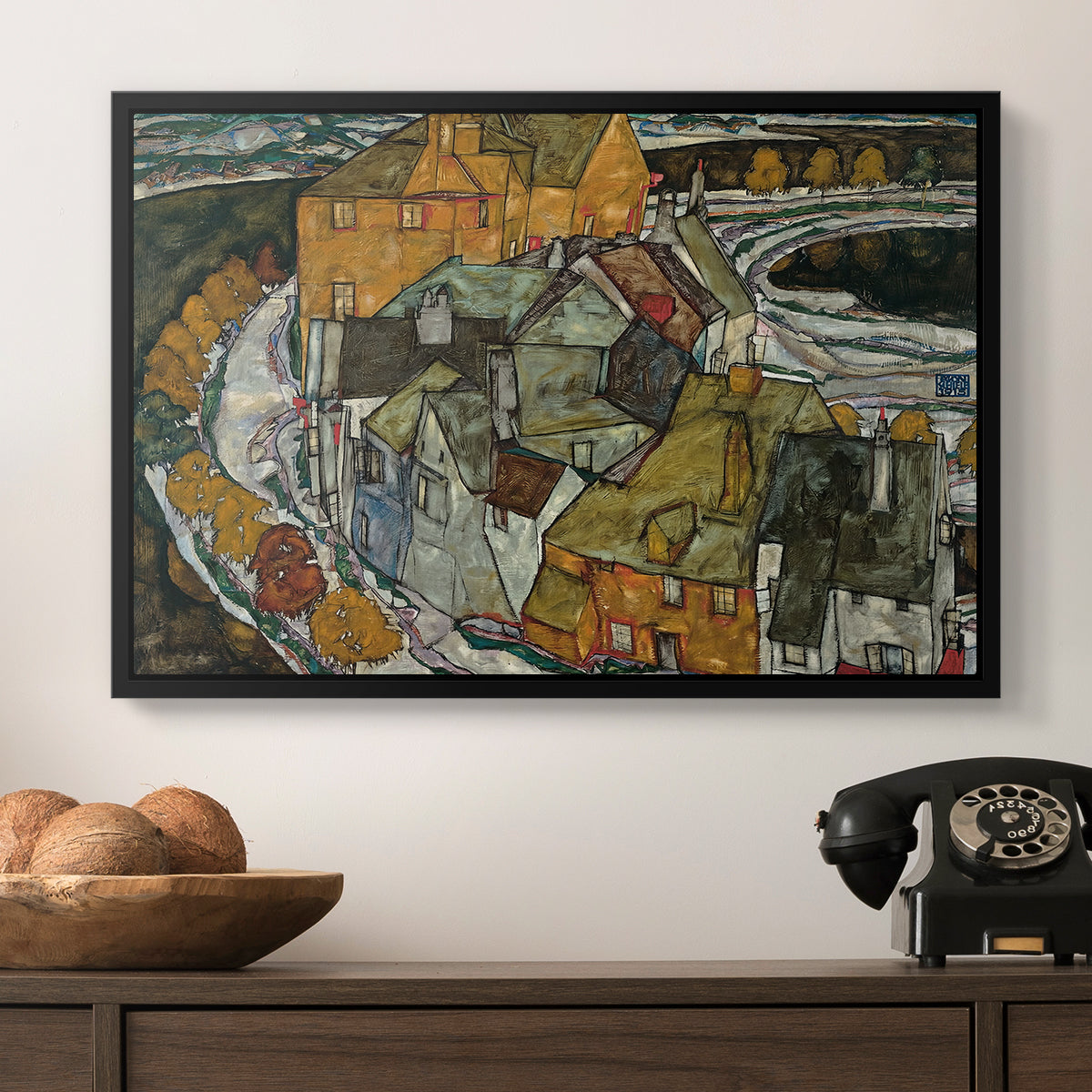 Crescent of Houses II (Island Town), 1915 by Egon Schiele in a black floater framed canvas displayed above a console table in a hallway, featuring an architectural scene with houses arranged in curved composition.