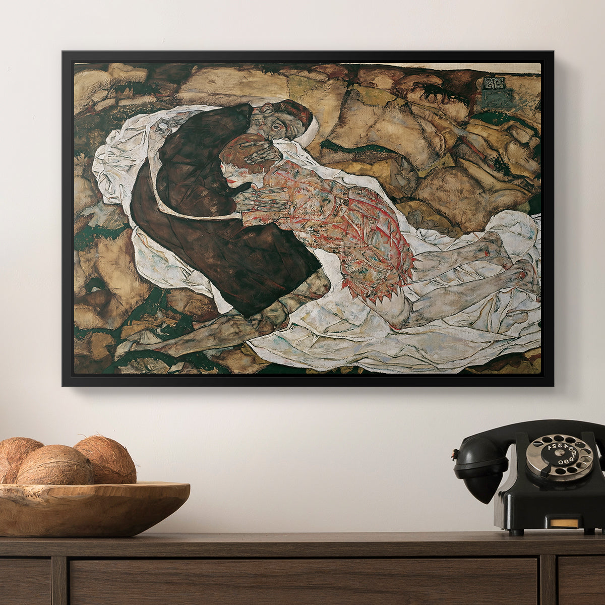 Death and the Maiden, 1915 by Egon Schiele in a black floater framed canvas displayed above a console table in a hallway, featuring an intense composition exploring life and death through figures.