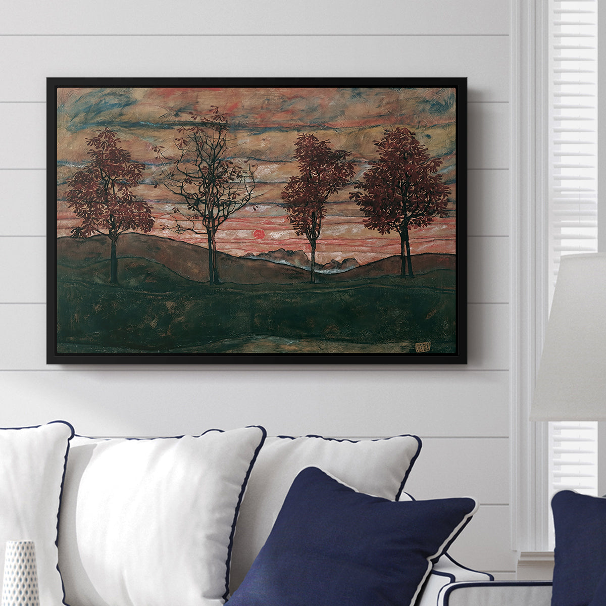 Four Trees, 1917 by Egon Schiele displayed above a sofa in a living room in a black floater frame, featuring a minimal landscape with grouped trees and expressive color.