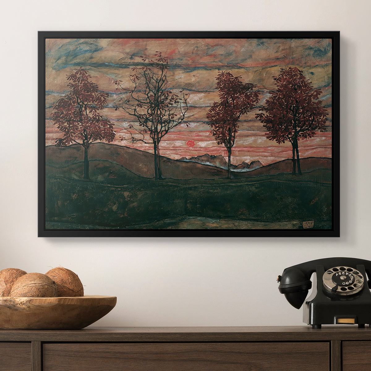 Four Trees, 1917 by Egon Schiele in a black floater framed canvas displayed above a console table in a hallway, featuring an expressionist landscape featuring isolated trees in field.