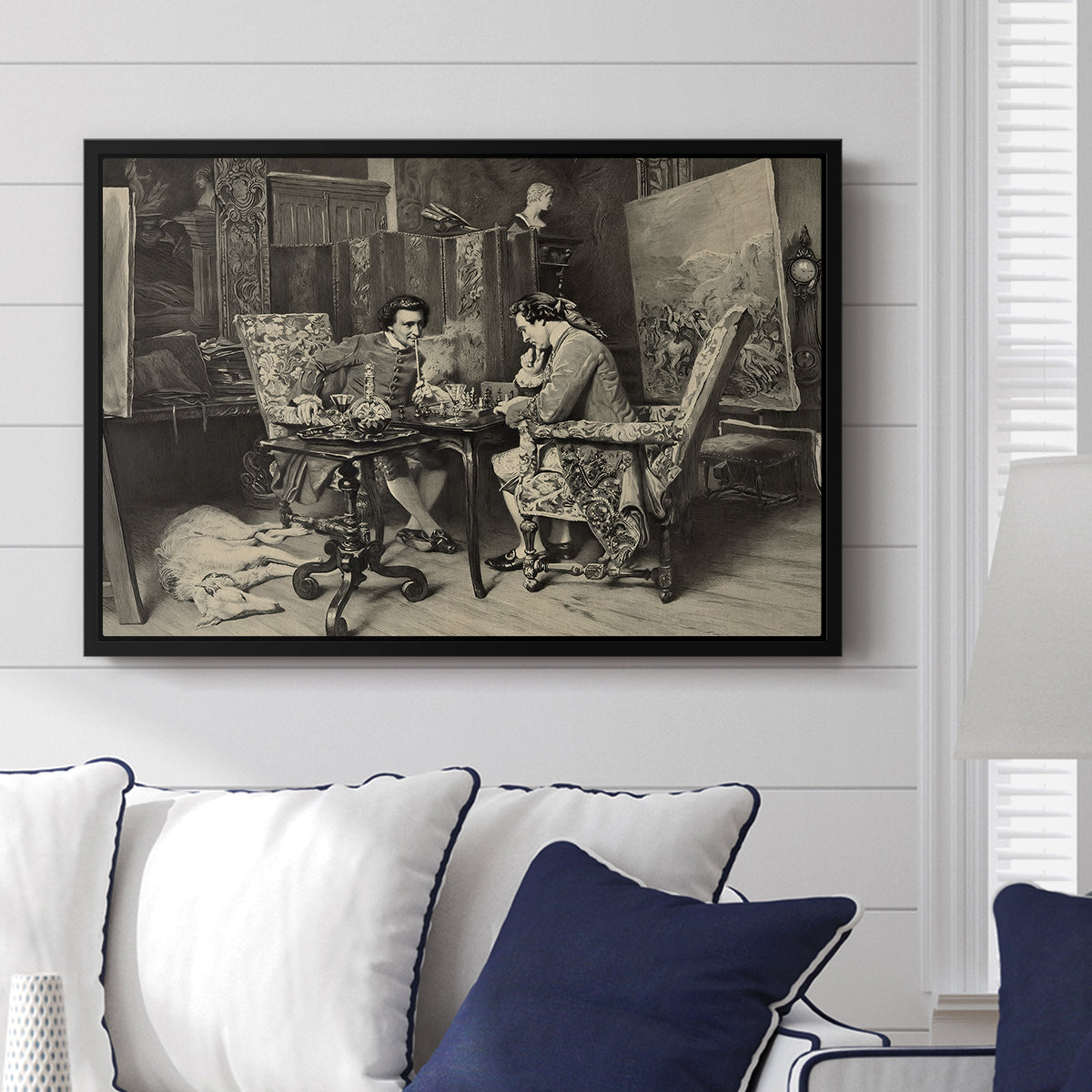 The Chess Players, 1858 by Ernest Meissonier displayed above a sofa in a living room in a black floater frame, featuring a realistic scene of figures concentrating on chess game indoors.