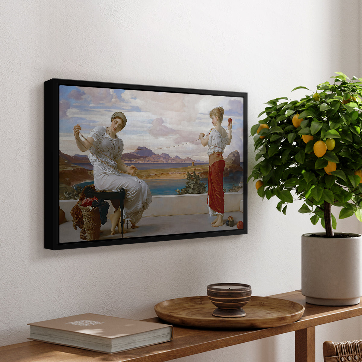 Winding the Skein, c. 1878 by Frederic Leighton, presented in a black floater framed canvas featuring a woman holding thread while another figure helps wind yarn in classical setting, displayed above a hallway console table.