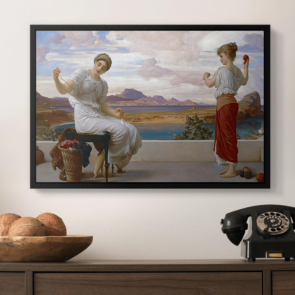 Winding the Skein, c. 1878 by Frederic Leighton in a black floater framed canvas displayed above a console table in a hallway, featuring an elegant composition of women performing domestic task.