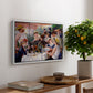 Luncheon of the Boating Party (Le Déjeuner des canotiers), 1880-1881 by Pierre-Auguste Renoir, presented in a white floater framed canvas featuring a group of elegantly dressed people dining together on a sunlit balcony overlooking the river, displayed above a hallway console table.