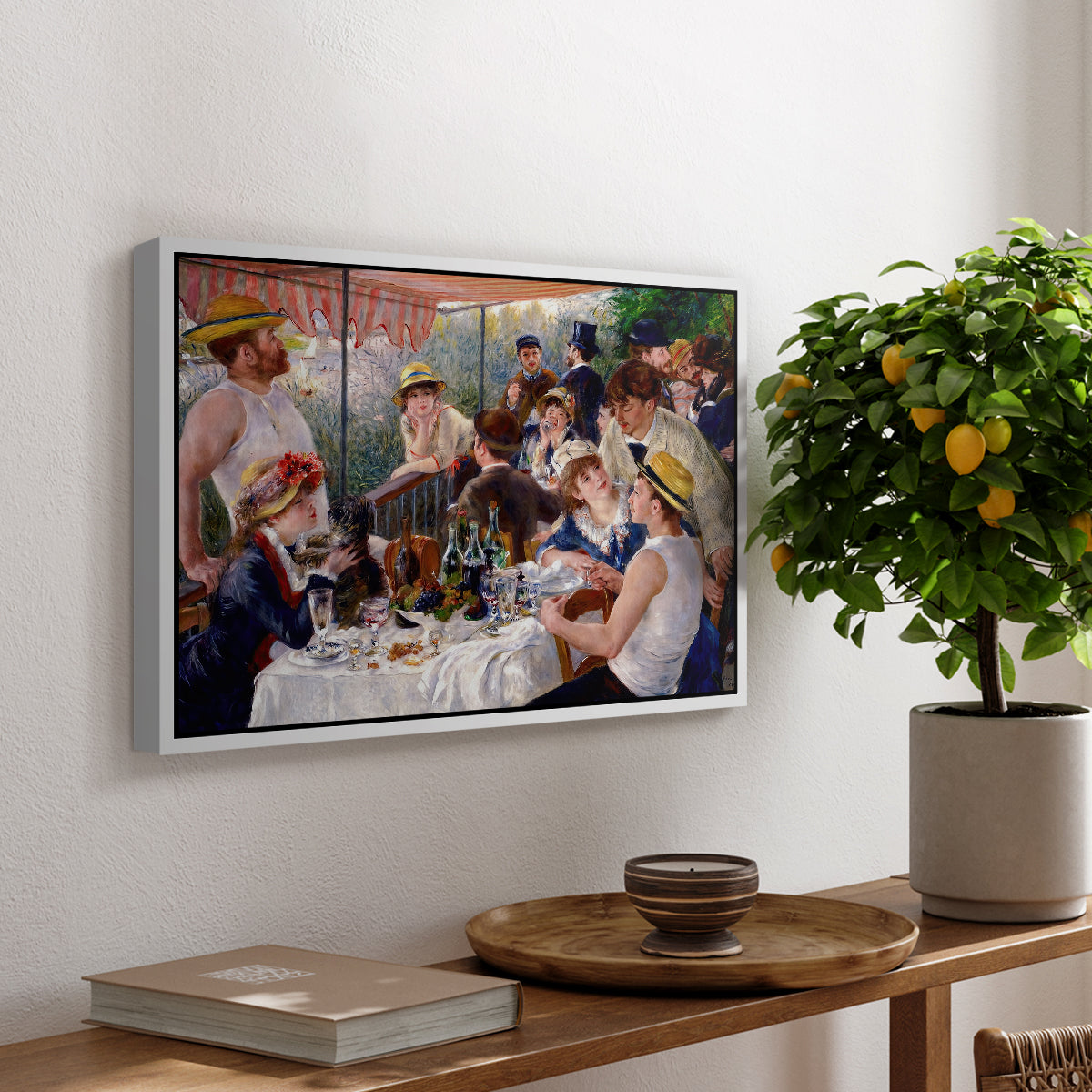 Luncheon of the Boating Party (Le Déjeuner des canotiers), 1880-1881 by Pierre-Auguste Renoir, presented in a white floater framed canvas featuring a group of elegantly dressed people dining together on a sunlit balcony overlooking the river, displayed above a hallway console table.