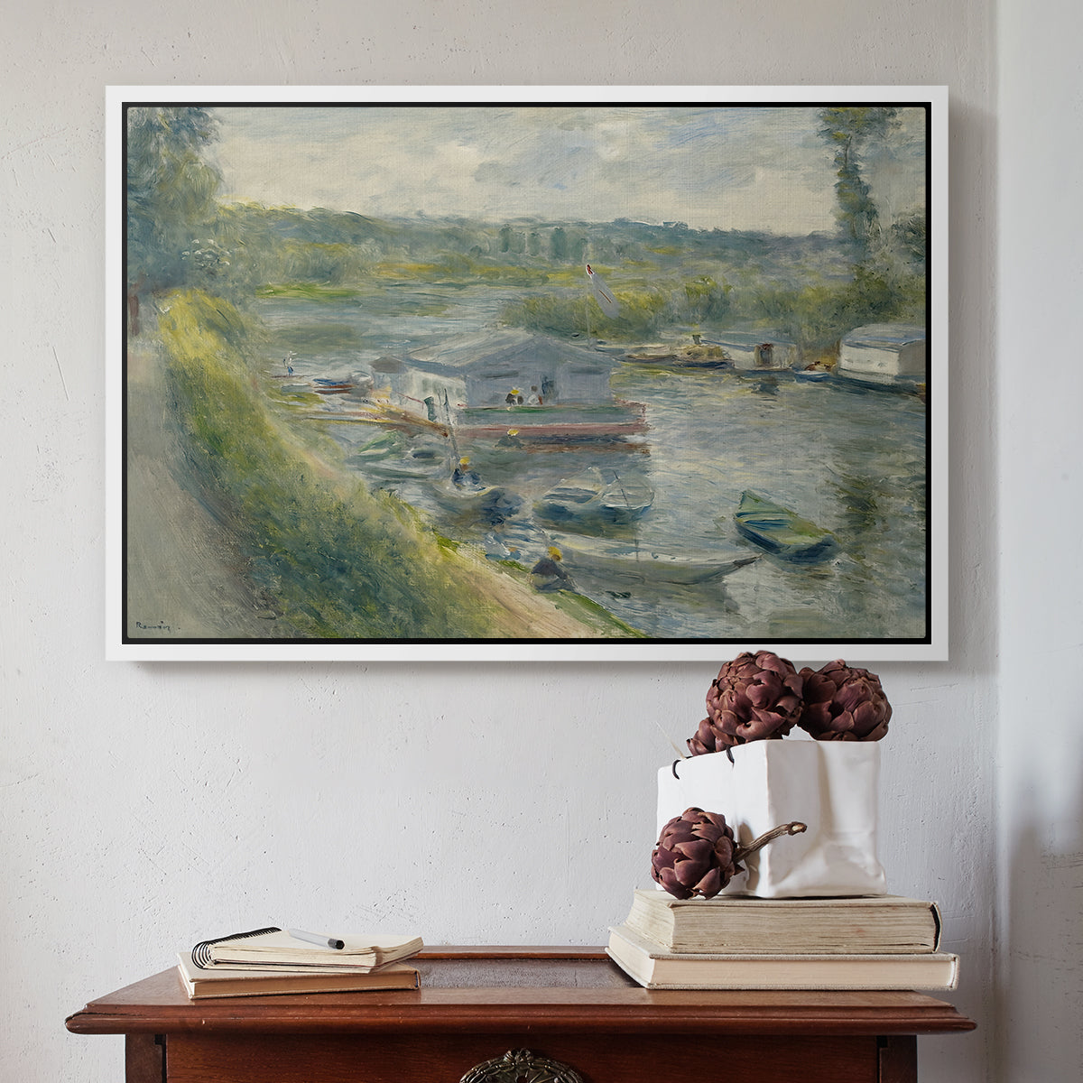 White floater framed canvas featuring Wash-House Boat at Bas-Meudon, c. 1874 by Pierre-Auguste Renoir above an entryway table in a minimalist foyer.