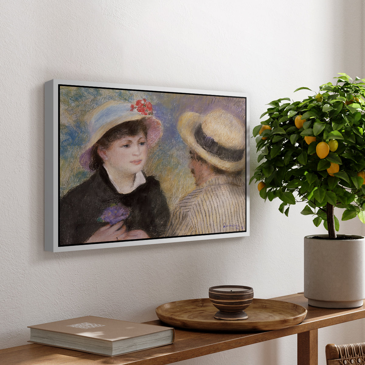 Boating Couple (Aline Charigot and Renoir), c. 1881 by Pierre-Auguste Renoir, presented in a white floater framed canvas featuring a close-up of a couple seated together outdoors with hats and soft sunlight, displayed above a hallway console table.