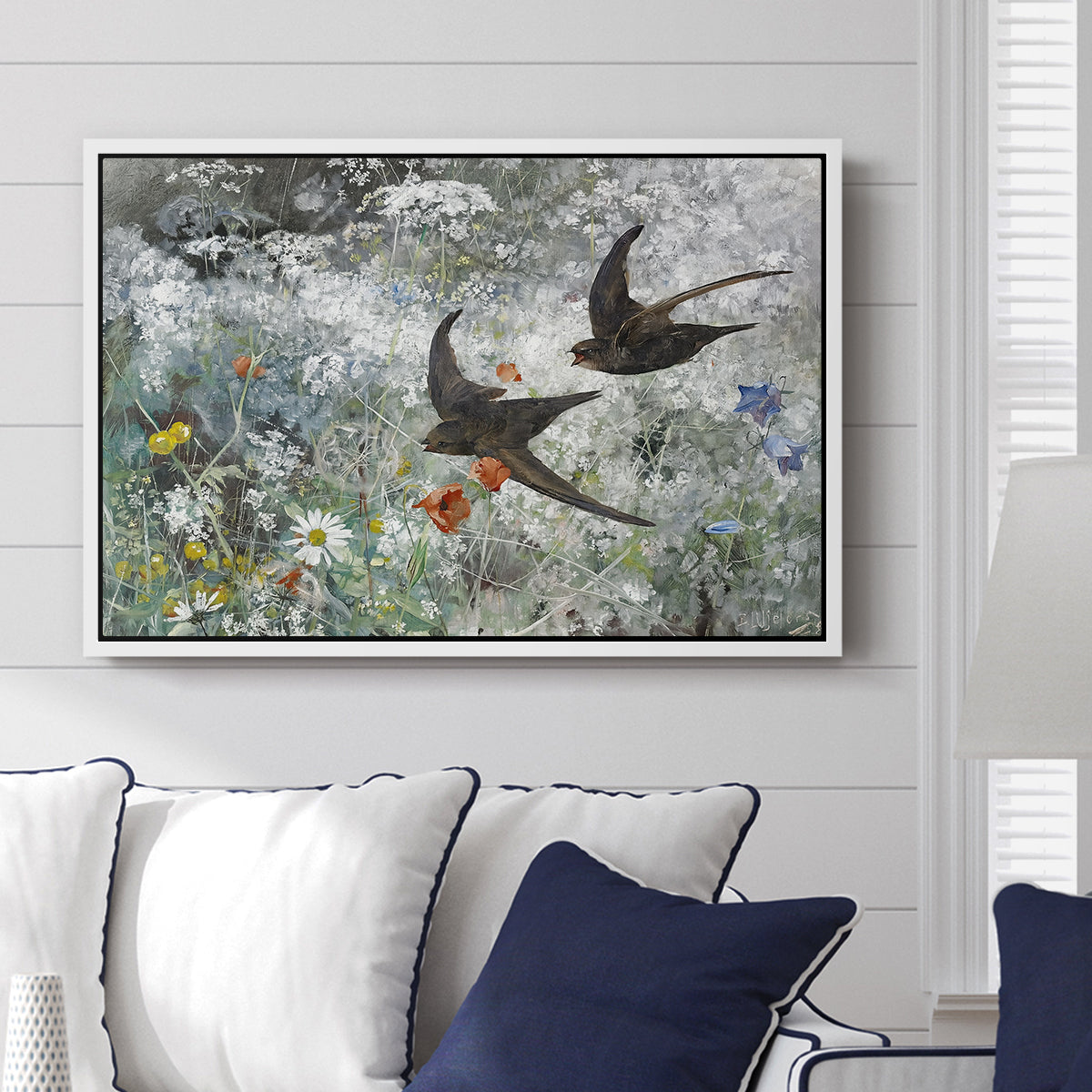 Common Swifts, 1886 by Bruno Liljefors displayed above a sofa in a living room in a white floater frame, featuring swifts gliding midair with wings spread against soft sky.