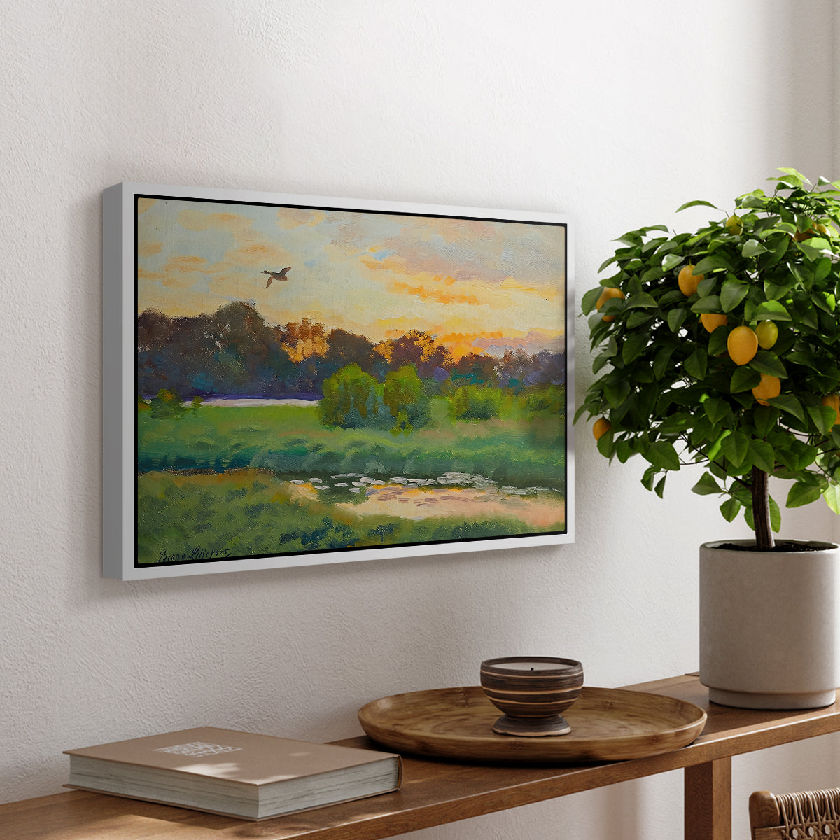 Flying Duck at Sunset, 1924 by Bruno Liljefors, presented in a white floater framed canvas featuring a wild duck flying over a sunset marsh with trees, displayed above a hallway console table.