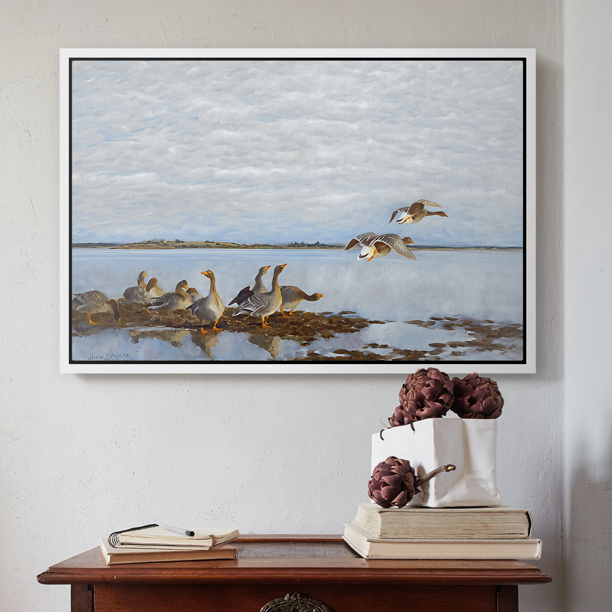 White floater framed canvas featuring Greylag Geese (Grågäss), 1922 by Bruno Liljefors above an entryway table in a minimalist foyer.