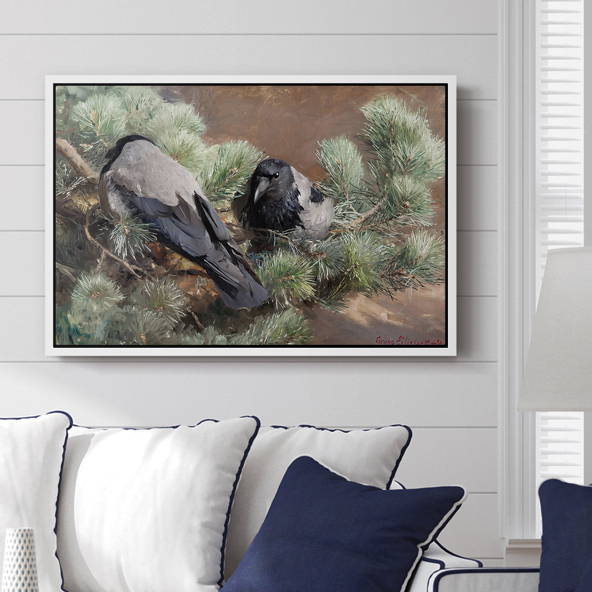 Hooded Crows (Kråkor), 1891 by Bruno Liljefors displayed above a sofa in a living room in a white floater frame, featuring birds standing alert in natural field environment.