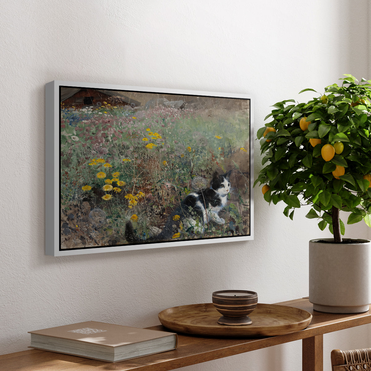 Cat on a Flowery Meadow, 1887 by Bruno Liljefors, presented in a white floater framed canvas featuring a cat crouching in a meadow filled with wildflowers and greenery, displayed above a hallway console table.