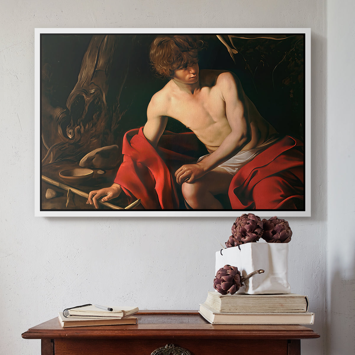 White floater framed canvas featuring Saint John the Baptist in the Wilderness, c. 1603-1604 by Caravaggio above an entryway table in a minimalist foyer.