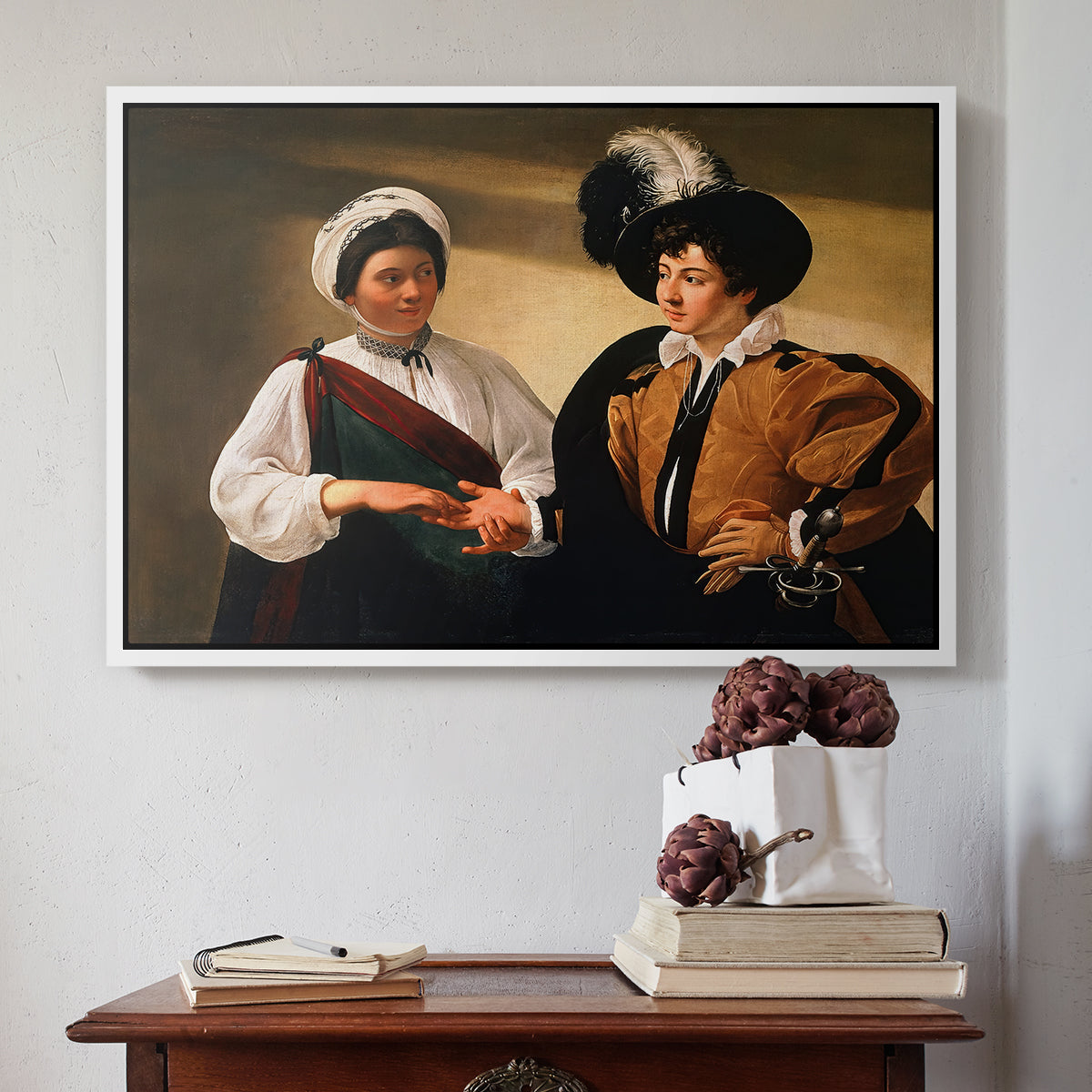 White floater framed canvas featuring The Fortune Teller (Louvre Version), c. 1595 by Caravaggio above an entryway table in a minimalist foyer.