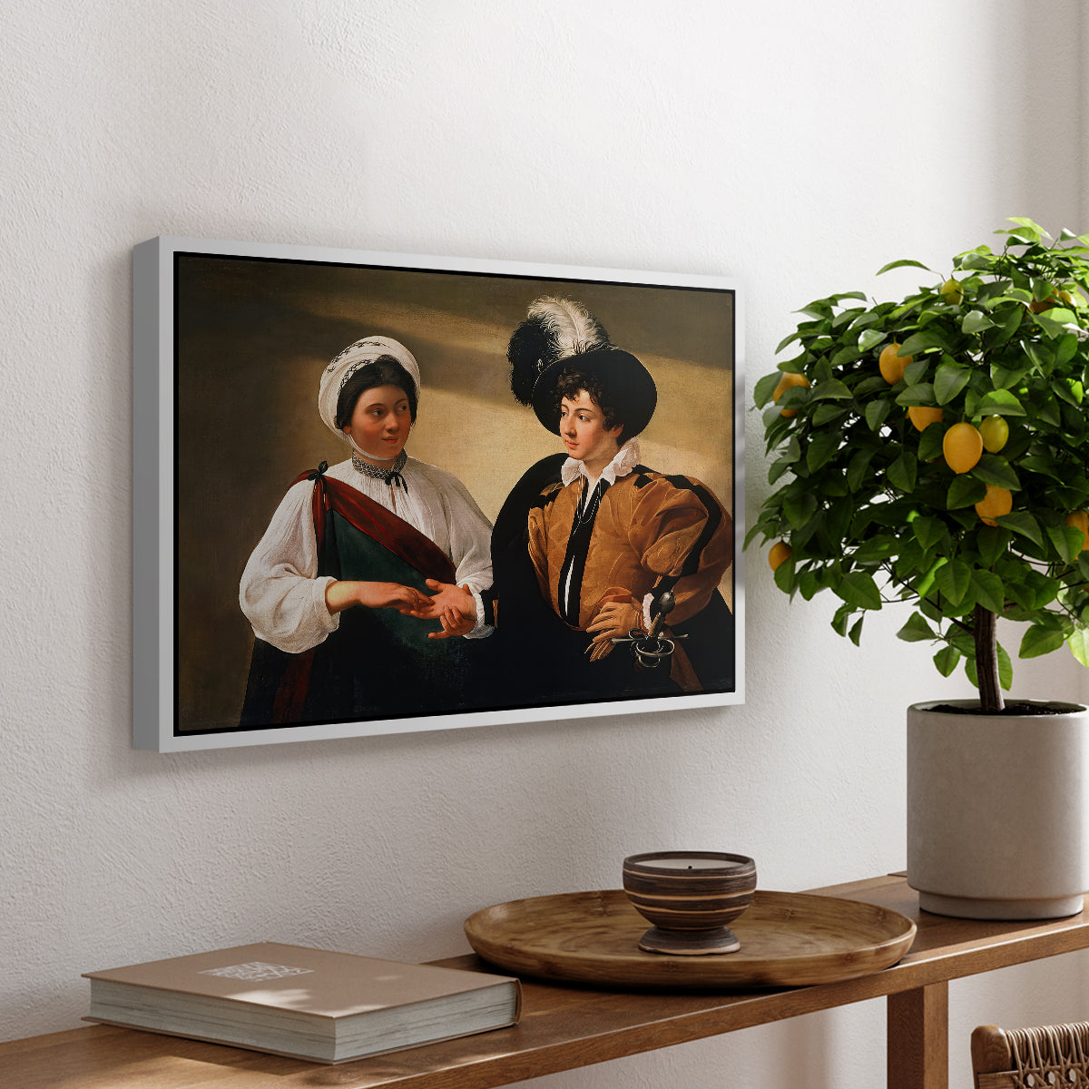 The Fortune Teller (Louvre Version), c. 1595 by Caravaggio, presented in a white floater framed canvas featuring a woman reading a young man's palm while secretly stealing his ring, displayed above a hallway console table.