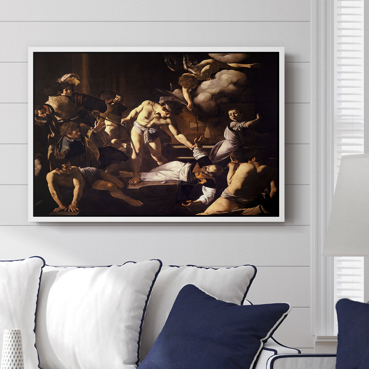 The Martyrdom of Saint Matthew, 1599-1600 by Caravaggio displayed above a sofa in a living room in a white floater frame, featuring a dramatic moment of martyrdom with figures reacting in panic.