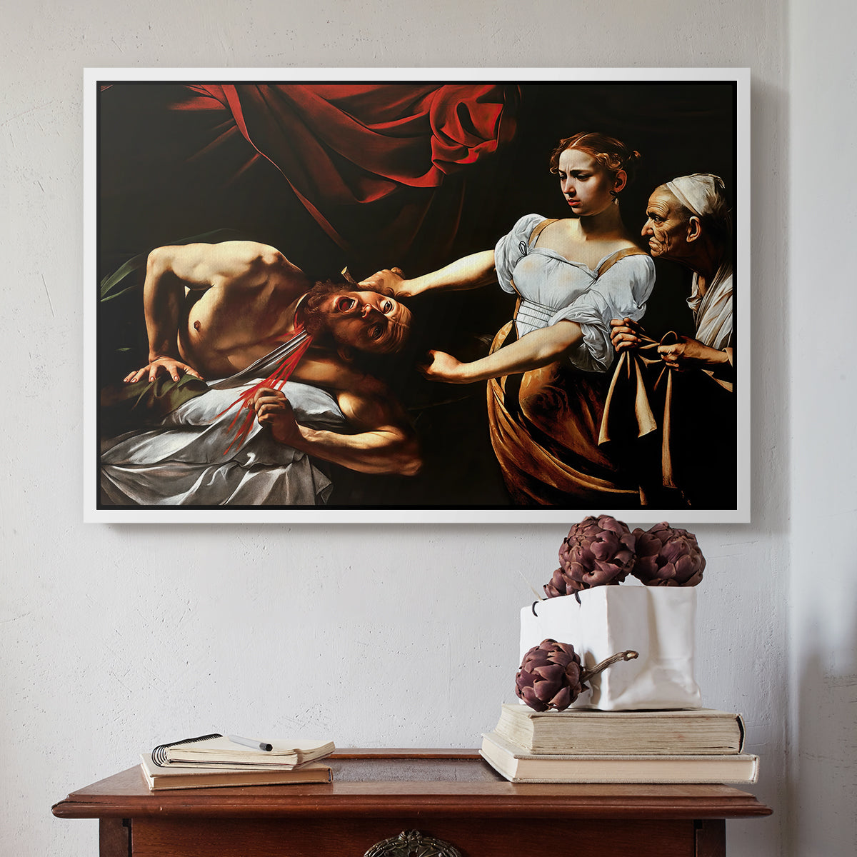 White floater framed canvas featuring Judith Beheading Holofernes, c. 1599 by Caravaggio above an entryway table in a minimalist foyer.