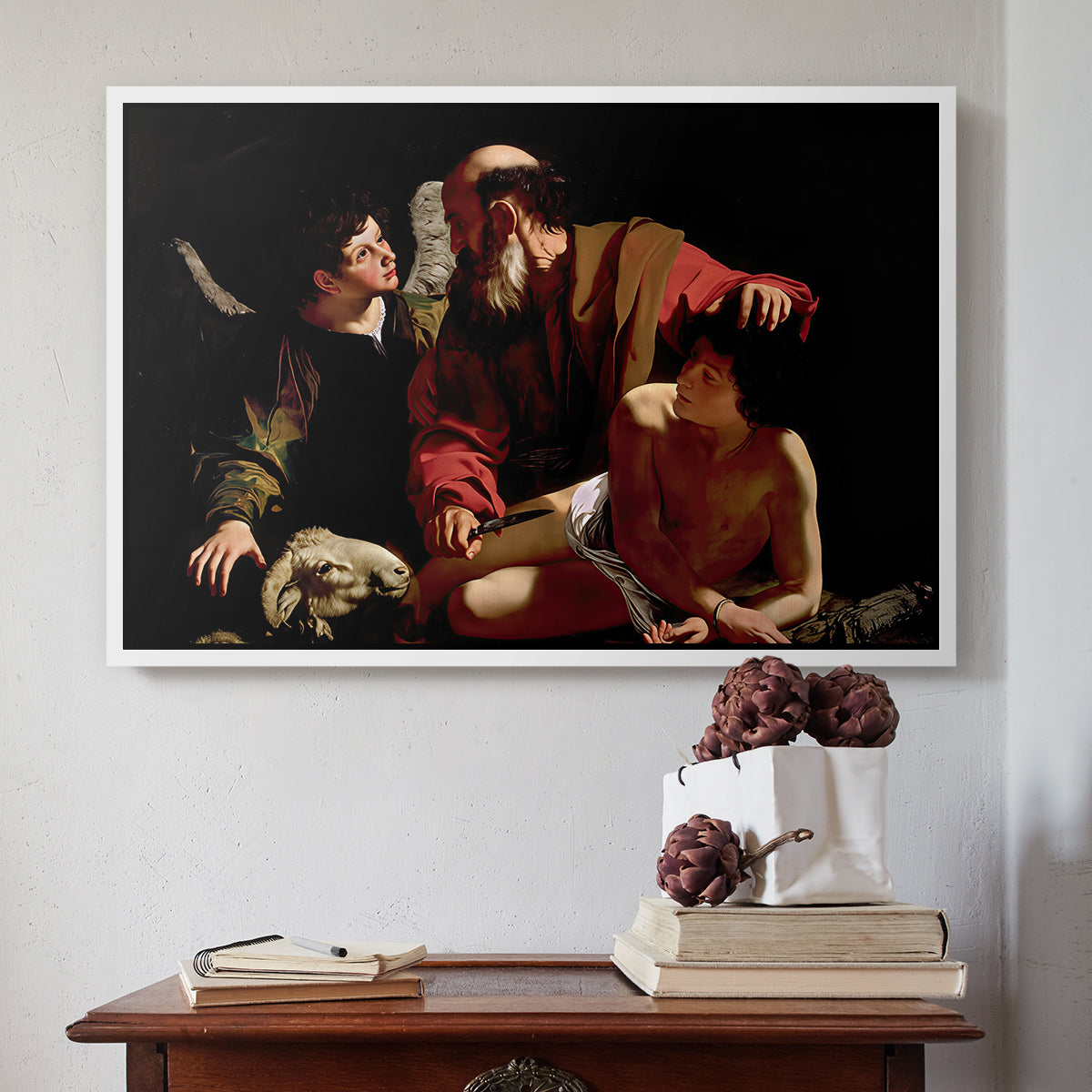 White floater framed canvas featuring The Sacrifice of Isaac (Uffizi Version), c. 1603 by Caravaggio above an entryway table in a minimalist foyer.