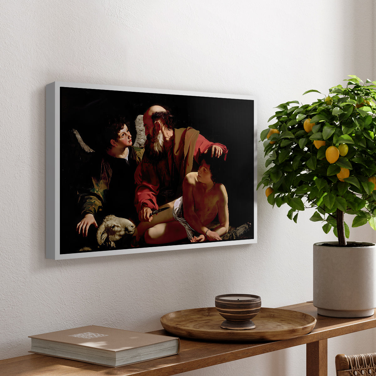 The Sacrifice of Isaac (Uffizi Version), c. 1603 by Caravaggio, presented in a white floater framed canvas featuring Abraham holding Isaac while angel intervenes to stop the sacrifice, displayed above a hallway console table.