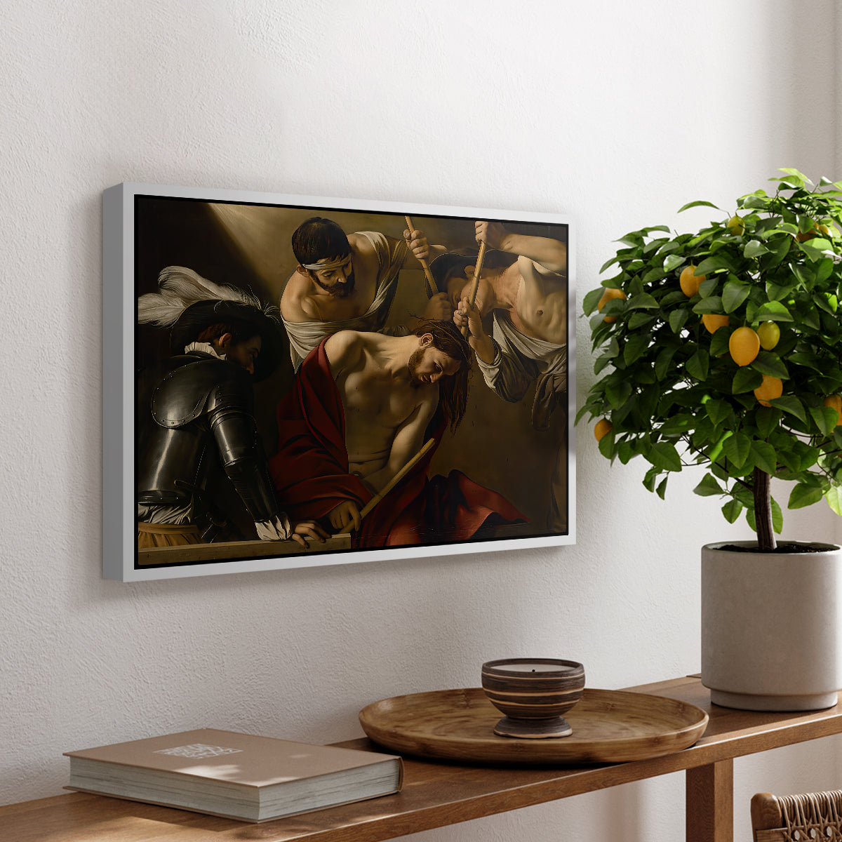 The Crowning with Thorns (Vienna Version), c. 1602-1604 by Caravaggio, presented in a white floater framed canvas featuring Christ surrounded by men pressing crown of thorns onto his head, displayed above a hallway console table.
