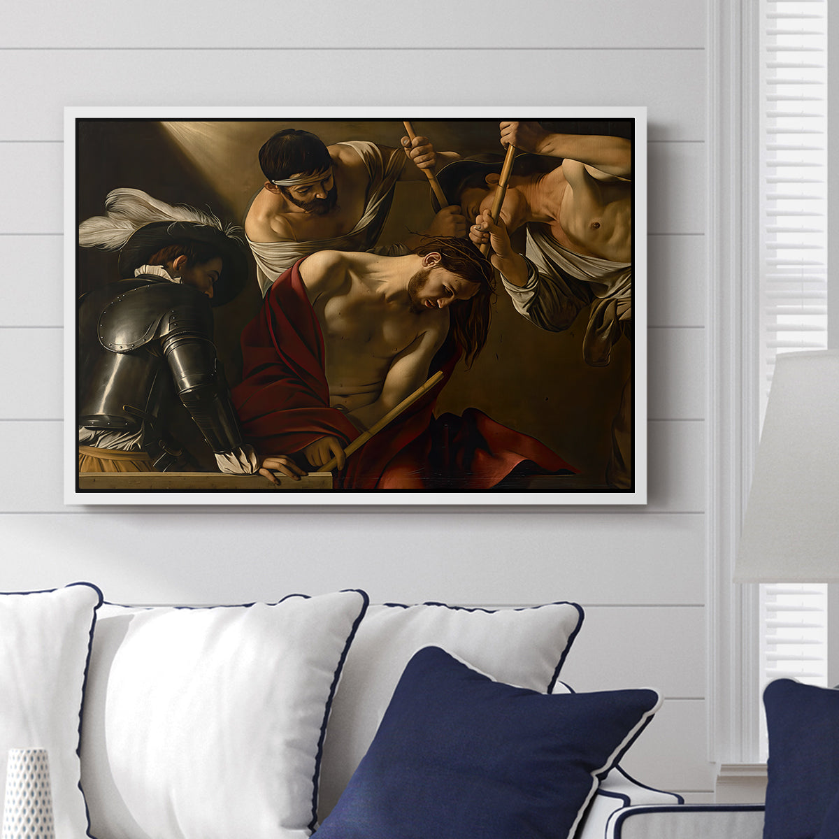 The Crowning with Thorns (Vienna Version), c. 1602-1604 by Caravaggio displayed above a sofa in a living room in a white floater frame, featuring a biblical scene of Christ being mocked and crowned with thorns.