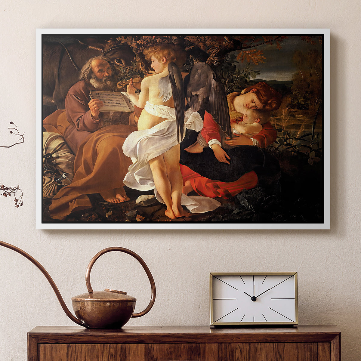 White floater framed canvas featuring a peaceful religious moment with figures reclining in natural setting, displayed above a cabinet in a soft-toned living room.