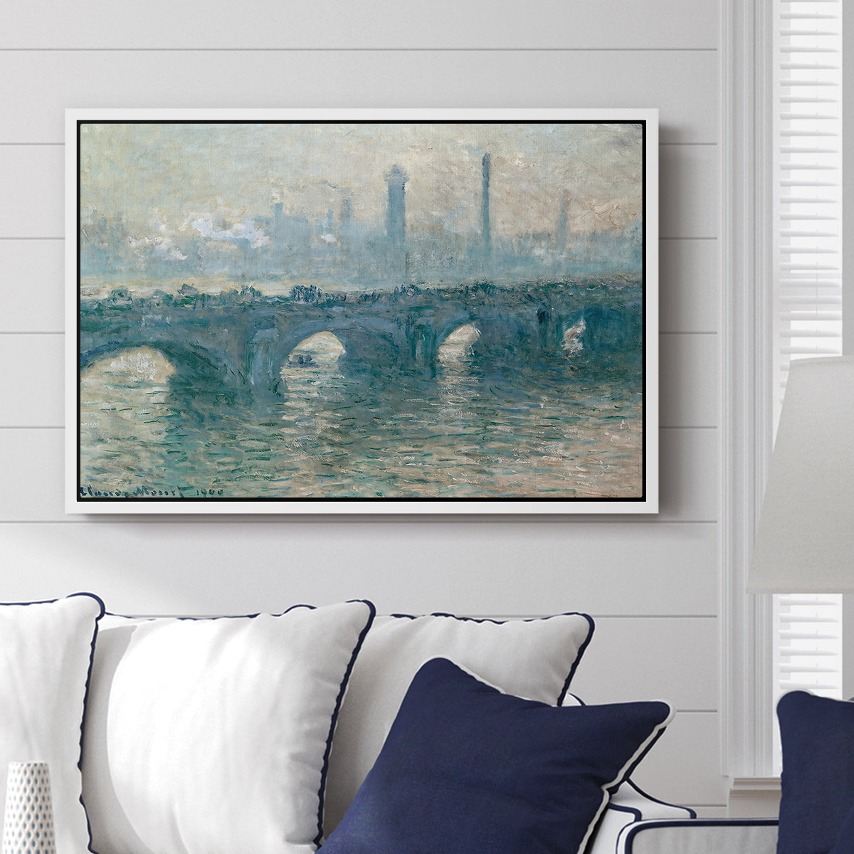 Waterloo Bridge, Gray Weather, 1900 by Claude Monet displayed above a sofa in a living room in a white floater frame, featuring an impressionist cityscape with bridge fading into fog over water.