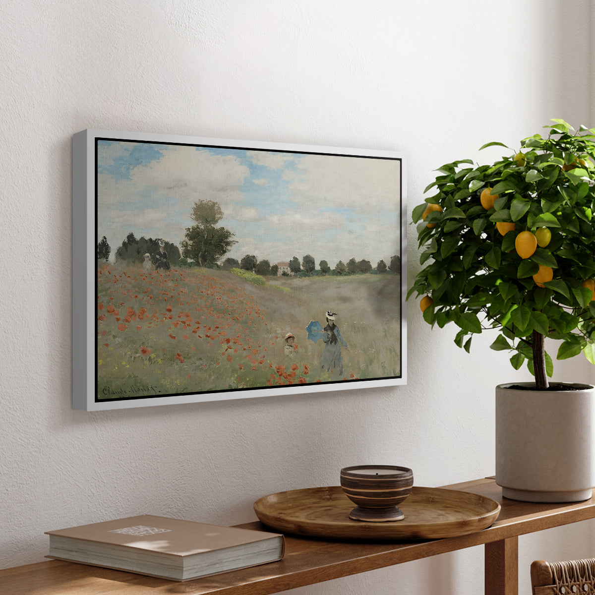 The Poppy Field near Argenteuil, 1873 by Claude Monet, presented in a white floater framed canvas featuring a field of red poppies with figures walking across rolling landscape, displayed above a hallway console table.