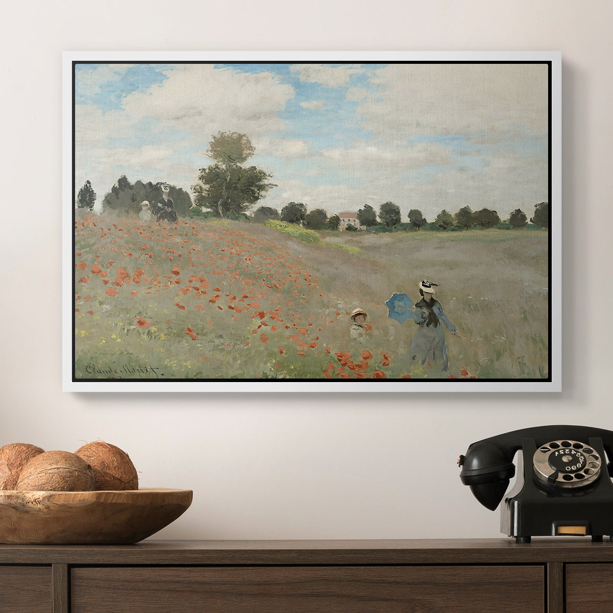 The Poppy Field near Argenteuil, 1873 by Claude Monet in a white floater framed canvas displayed above a console table in a hallway, featuring a rural landscape with scattered figures among blooming flowers.