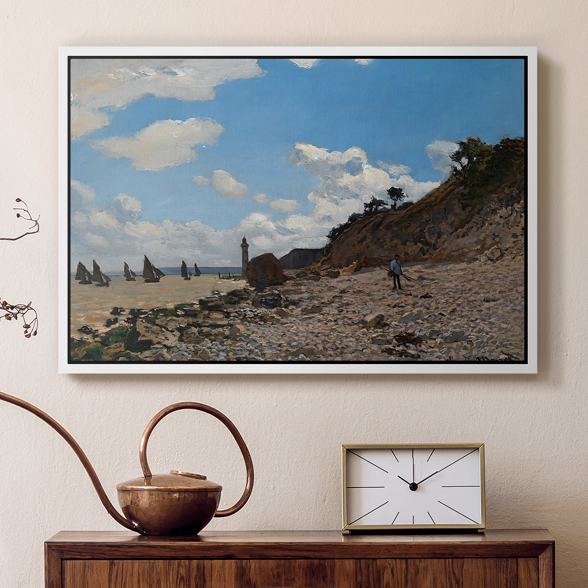 White floater framed canvas featuring a sandy beach with figures relaxing near water's edge, displayed above a cabinet in a soft-toned living room.