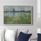 Banks of the Seine, Vétheuil, 1880 by Claude Monet displayed above a sofa in a living room in a white floater frame, featuring an impressionist view of Seine with reflections and greenery.