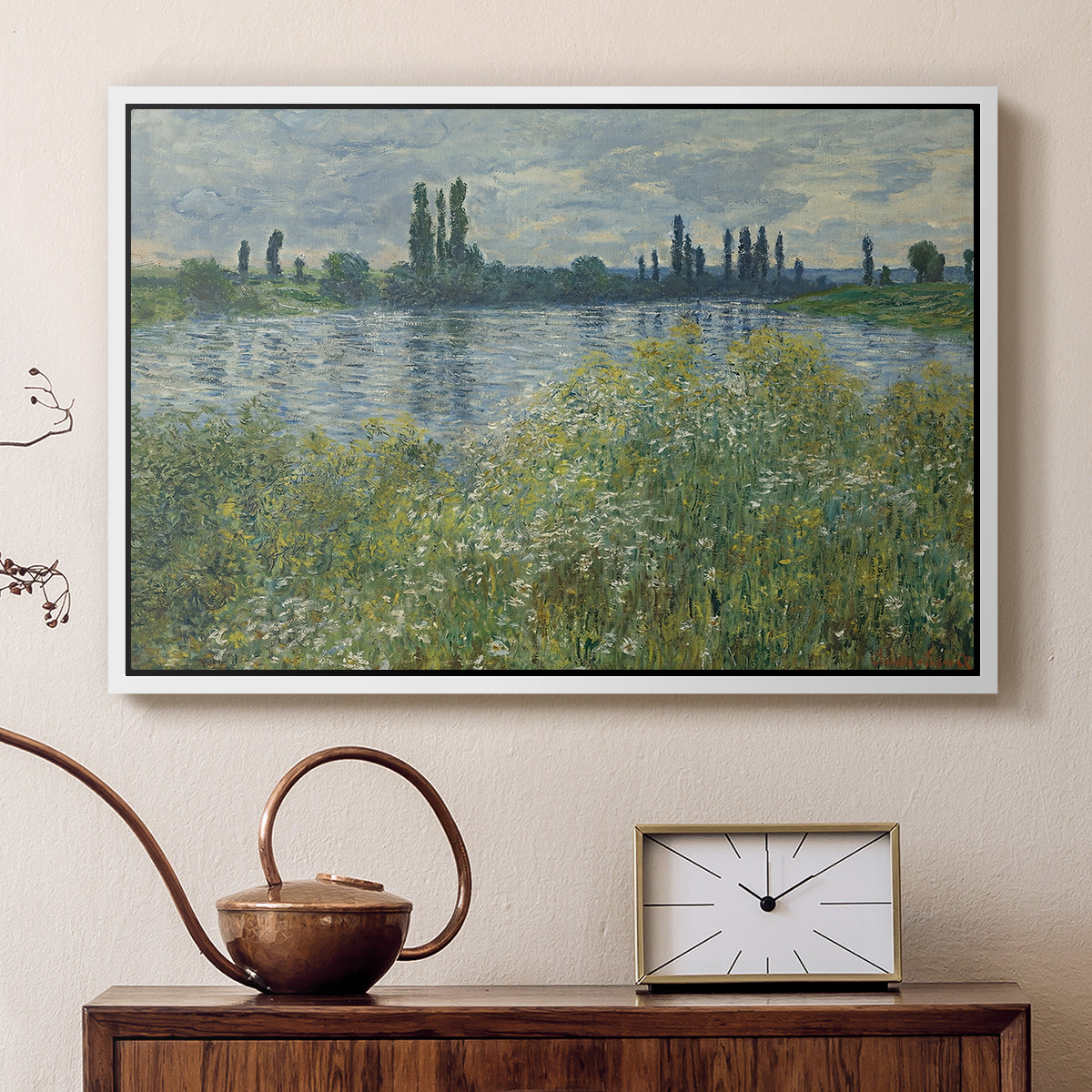 White floater framed canvas featuring a tranquil riverside scene with houses and vegetation, displayed above a cabinet in a soft-toned living room.