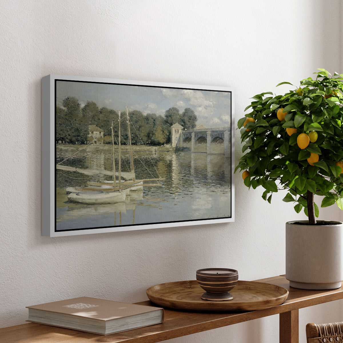 The Bridge at Argenteuil, 1874 by Claude Monet, presented in a white floater framed canvas featuring a bridge spanning river with sailboats and reflections in water, displayed above a hallway console table.