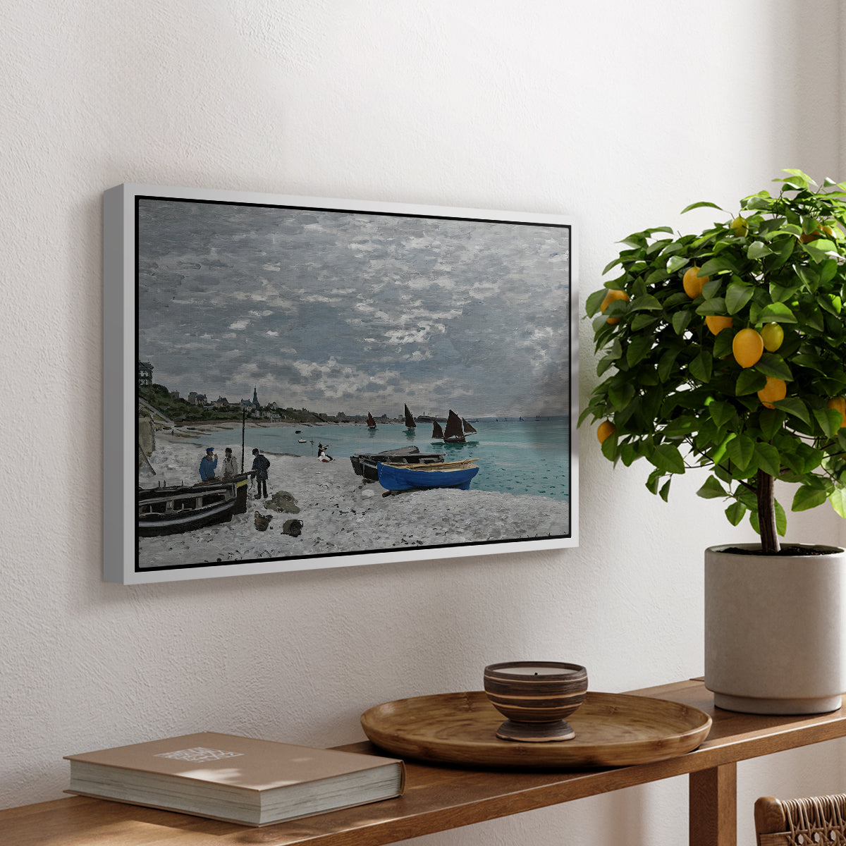 The Beach at Sainte-Adresse, 1867 by Claude Monet, presented in a white floater framed canvas featuring a seaside promenade with figures, flags, and boats along the coast, displayed above a hallway console table.