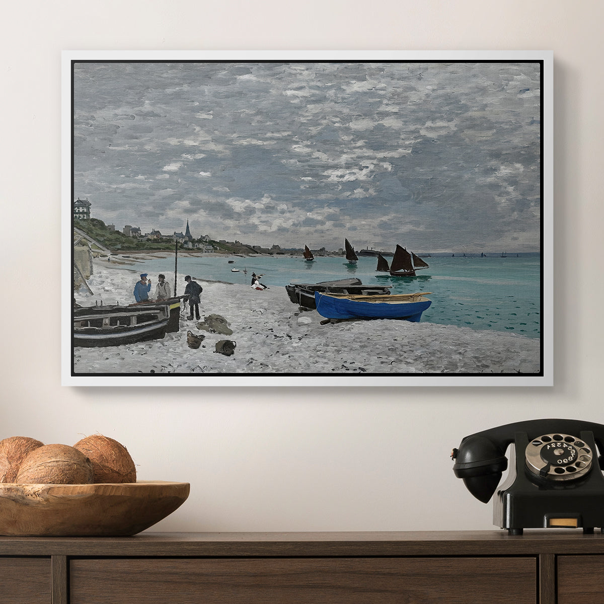 The Beach at Sainte-Adresse, 1867 by Claude Monet in a white floater framed canvas displayed above a console table in a hallway, featuring an impressionist seaside gathering with flags and ocean view.