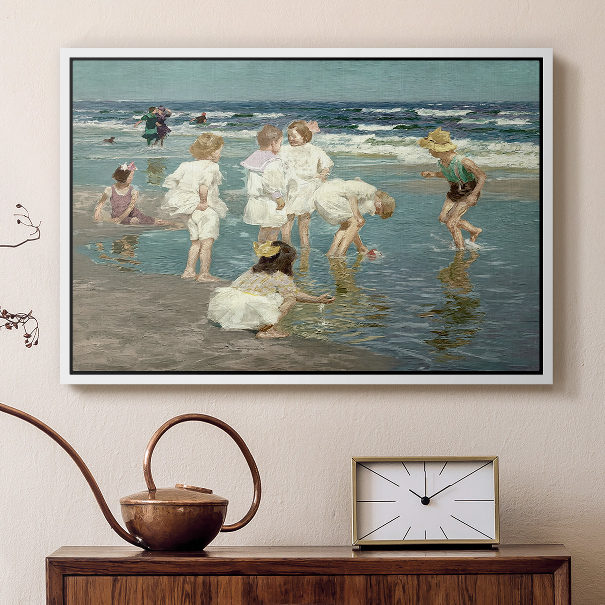 White floater framed canvas featuring an impressionist coastal view of families enjoying seaside water, displayed above a cabinet in a soft-toned living room.