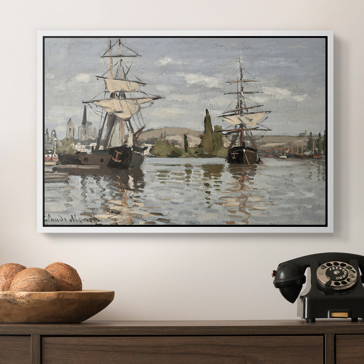 Ships Riding on the Seine at Rouen, 1872 by Claude Monet in a white floater framed canvas displayed above a console table in a hallway, featuring a nautical landscape with vessels resting on calm water.