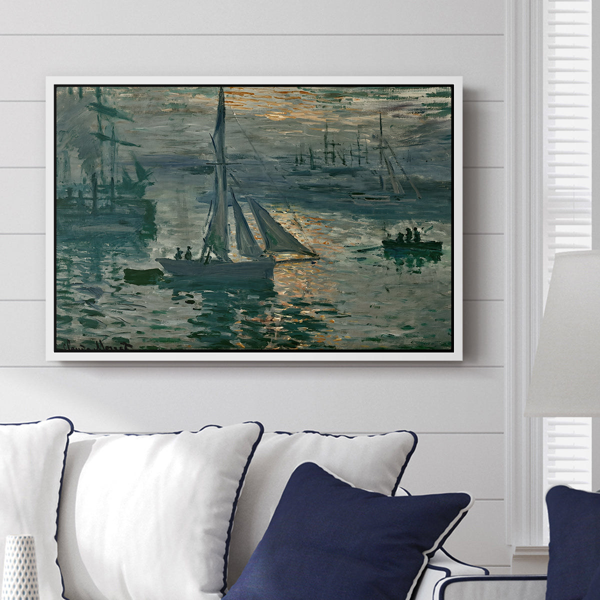 Sunrise (Marine), 1873 by Claude Monet displayed above a sofa in a living room in a white floater frame, featuring an impressionist seascape with glowing sun and misty water.