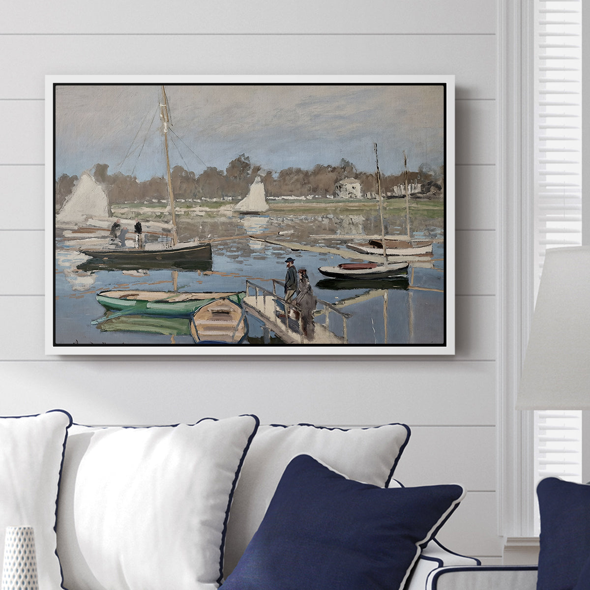 The Basin at Argenteuil, 1874 by Claude Monet displayed above a sofa in a living room in a white floater frame, featuring an impressionist boating scene with clustered masts and gentle ripples.