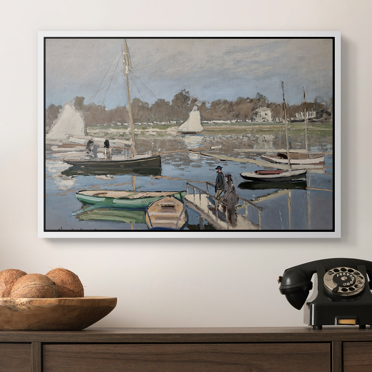 The Basin at Argenteuil, 1874 by Claude Monet in a white floater framed canvas displayed above a console table in a hallway, featuring a tranquil river setting with sailboats and shoreline.