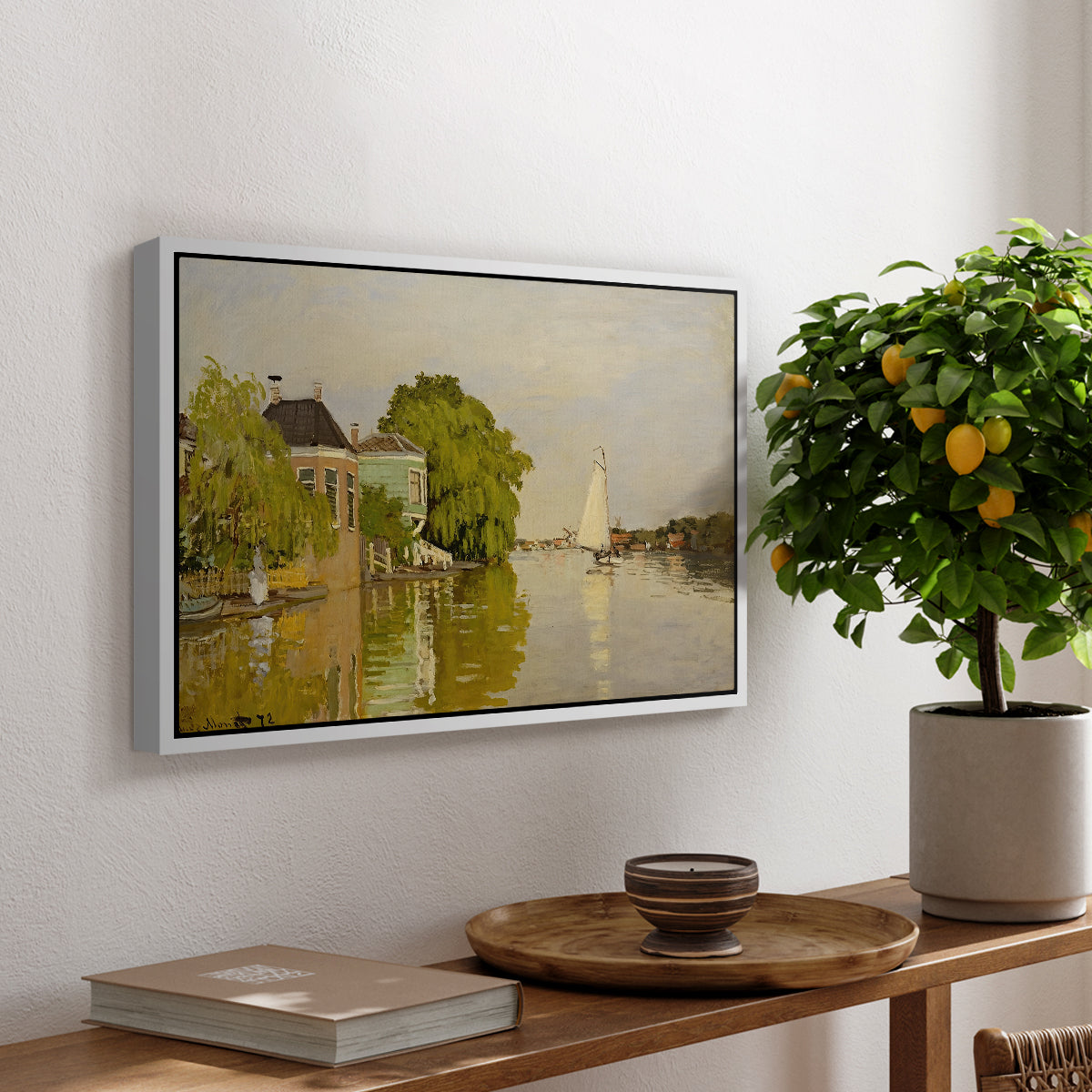 Houses on the Achterzaan, 1871 by Claude Monet, presented in a white floater framed canvas featuring colorful houses reflected in calm river surrounded by greenery, displayed above a hallway console table.