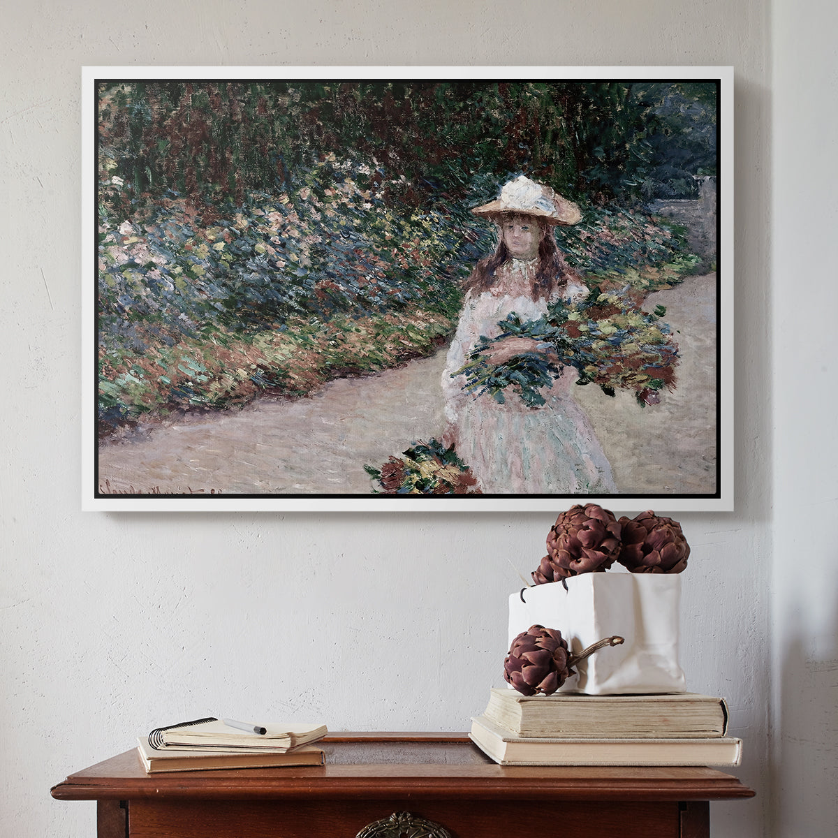 White floater framed canvas featuring Young Girl in the Garden at Giverny, 1888 by Claude Monet above an entryway table in a minimalist foyer.