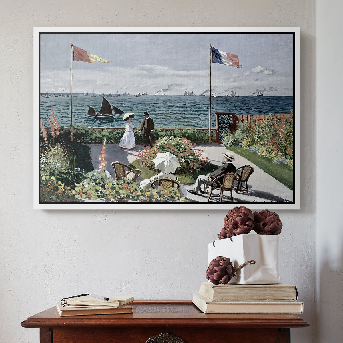 White floater framed canvas featuring Garden at Sainte-Adresse, 1867 by Claude Monet above an entryway table in a minimalist foyer.