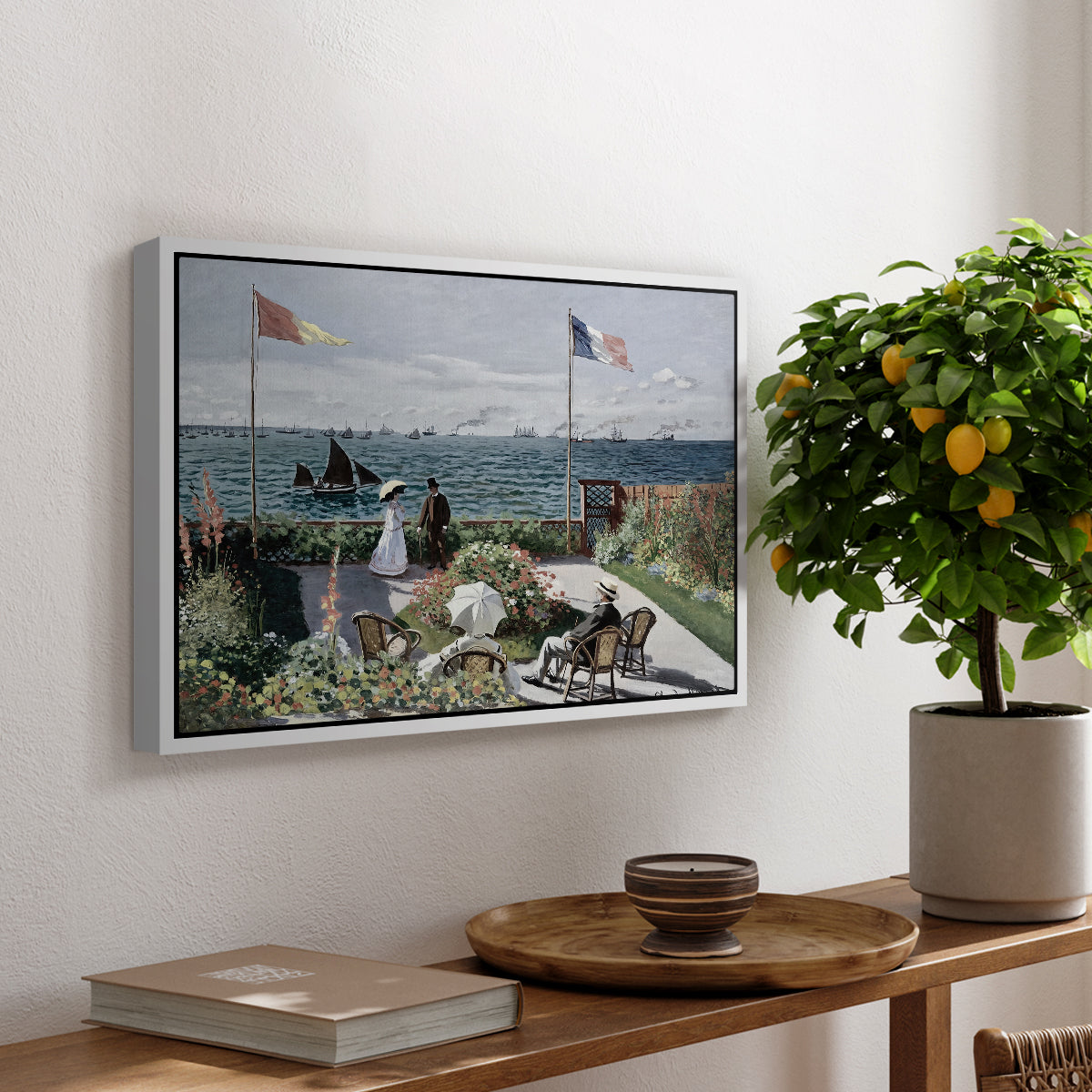 Garden at Sainte-Adresse, 1867 by Claude Monet, presented in a white floater framed canvas featuring a seaside garden with flowers, flags, and figures overlooking the water, displayed above a hallway console table.