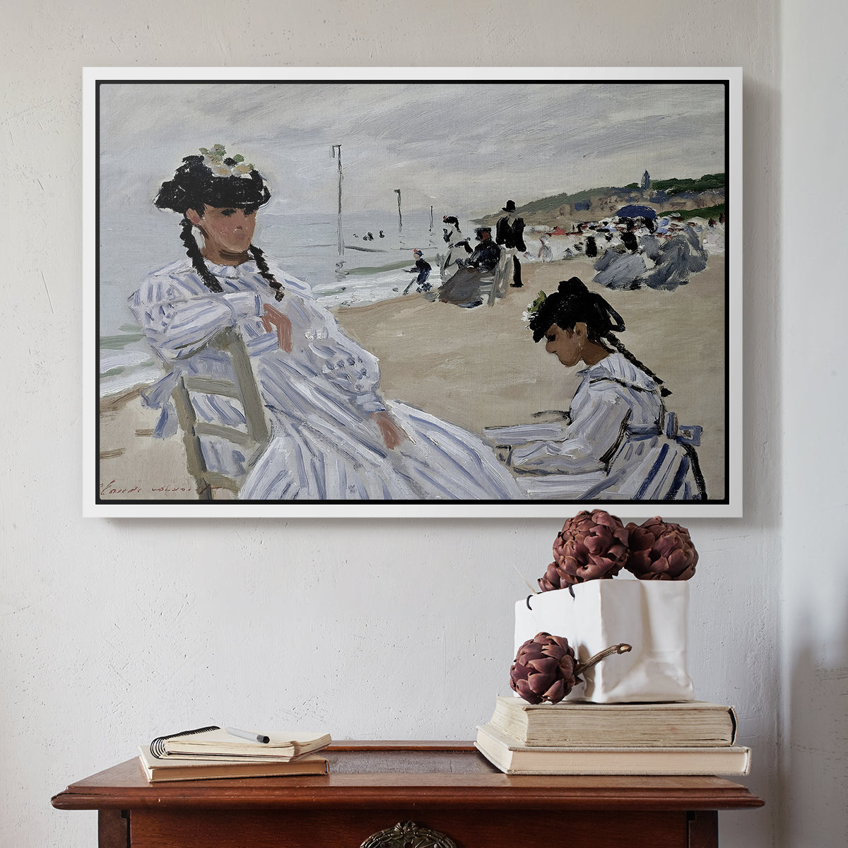 White floater framed canvas featuring On the Beach at Trouville, 1870 by Claude Monet above an entryway table in a minimalist foyer.