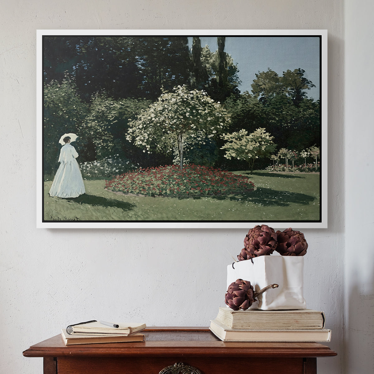 White floater framed canvas featuring Woman in the Garden, Sainte-Adresse, 1867 by Claude Monet above an entryway table in a minimalist foyer.