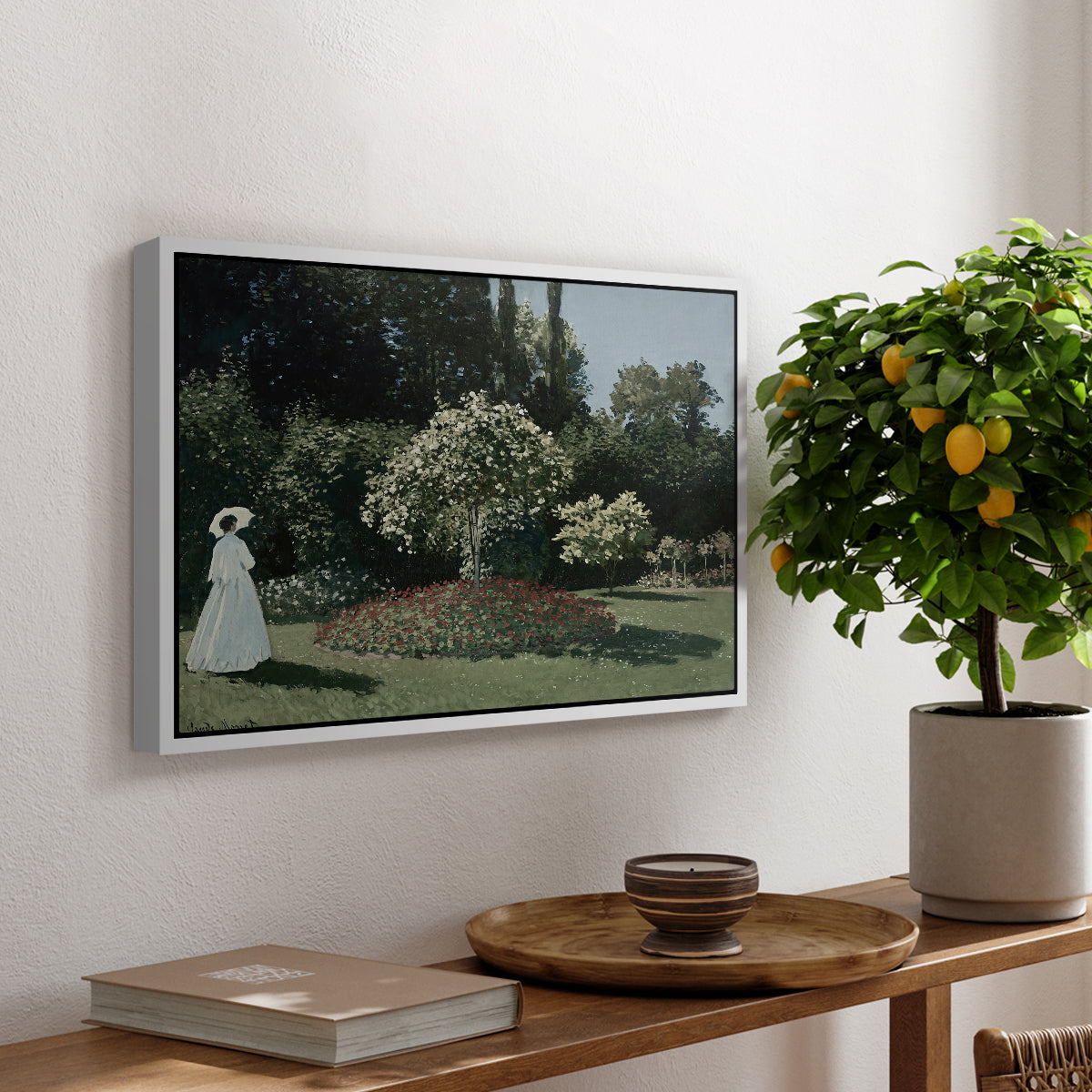 Woman in the Garden, Sainte-Adresse, 1867 by Claude Monet, presented in a white floater framed canvas featuring a woman standing in garden surrounded by flowers and greenery, displayed above a hallway console table.