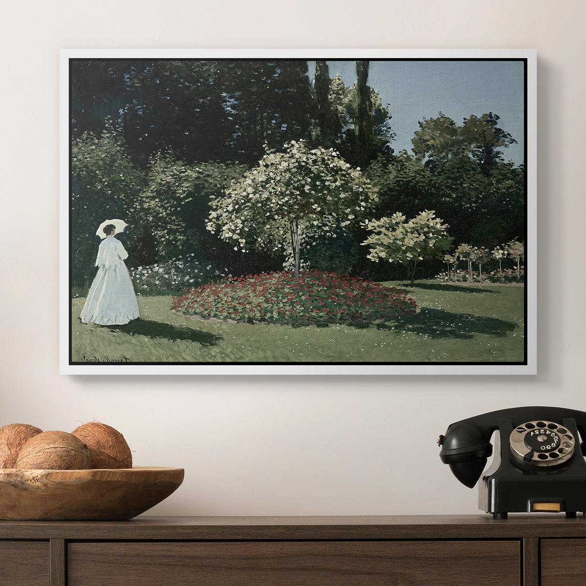 Woman in the Garden, Sainte-Adresse, 1867 by Claude Monet in a white floater framed canvas displayed above a console table in a hallway, featuring a tranquil garden portrait with soft natural light.